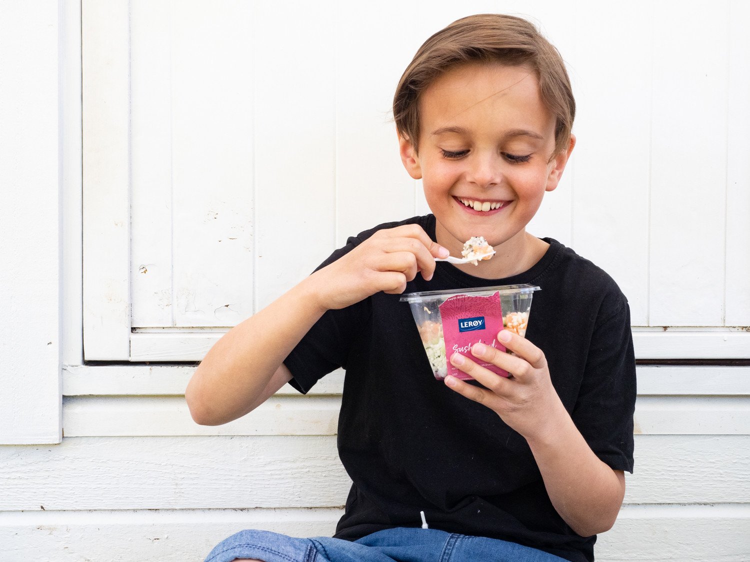 Gutt smiler og spiser poké bowl med laks fra Lerøy